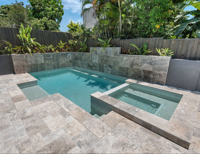 Small pool with stone deck and surrounding greenery